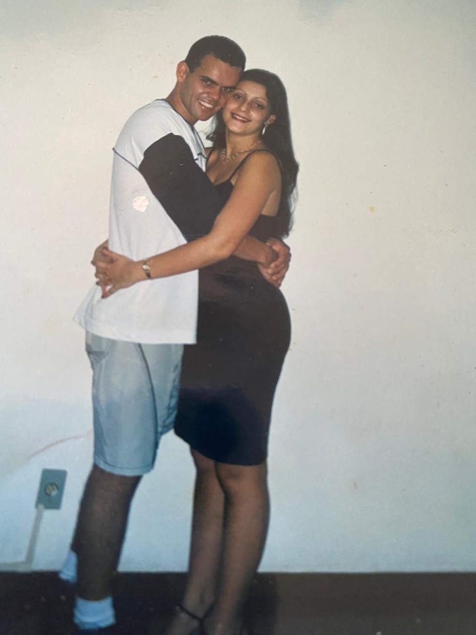 Drica e Sergio jovens, abraçados e sorrindo.